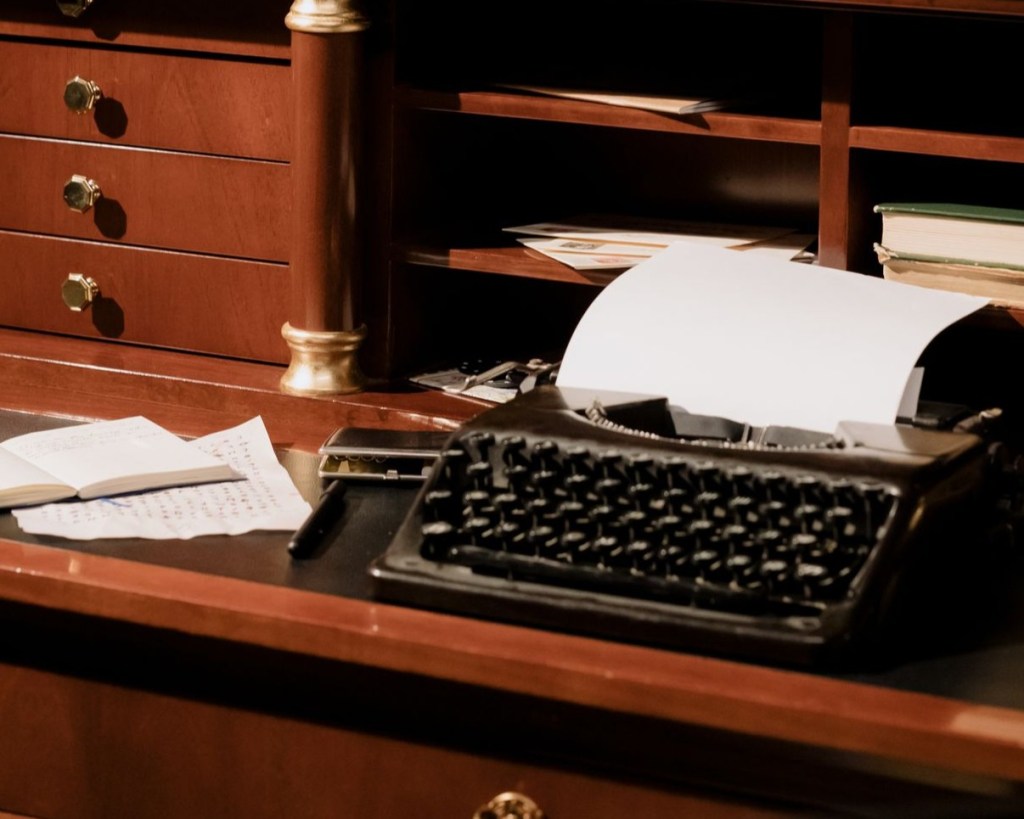 A typewriter on an antique wood desk.