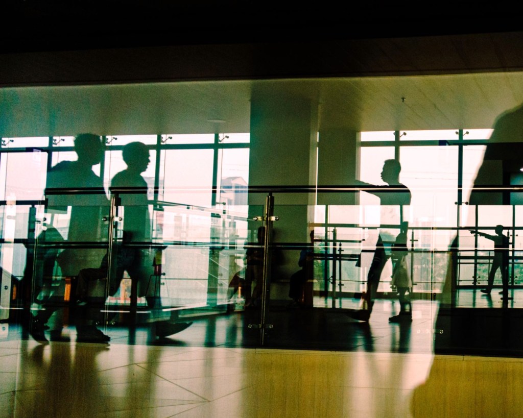 A picture capturing the reflections of people in glass as they walk through a school.